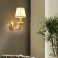 Alessio fabric wall sconce, single arm beside a palm and pale column