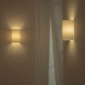Zenform Glow fabric wall sconce, two linen cylinders by sheer curtains in a dim room