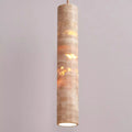 Cream stone tube pendant light glowing on a mauve backdrop