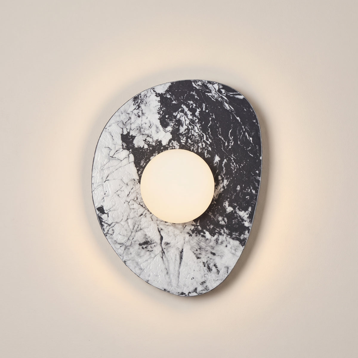 Aurora Slab marble wall sconce, black and white stone with opal globe, studio shot on a neutral backdrop