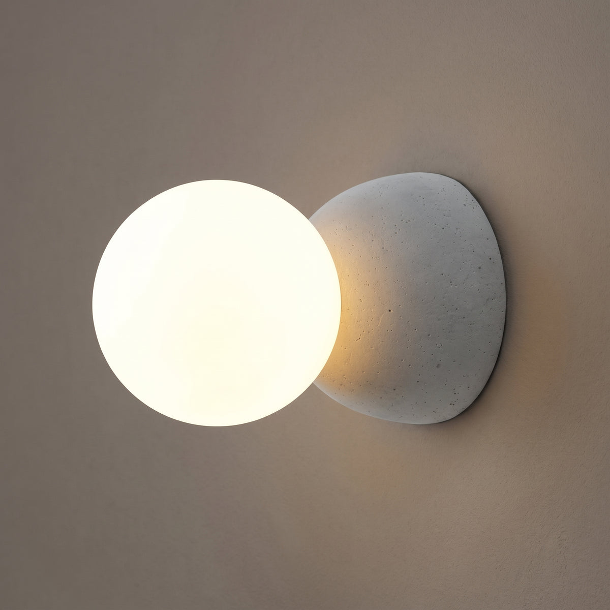 Circle of Light glass wall sconce in concrete grey, opal globe lit, studio shot on a neutral backdrop