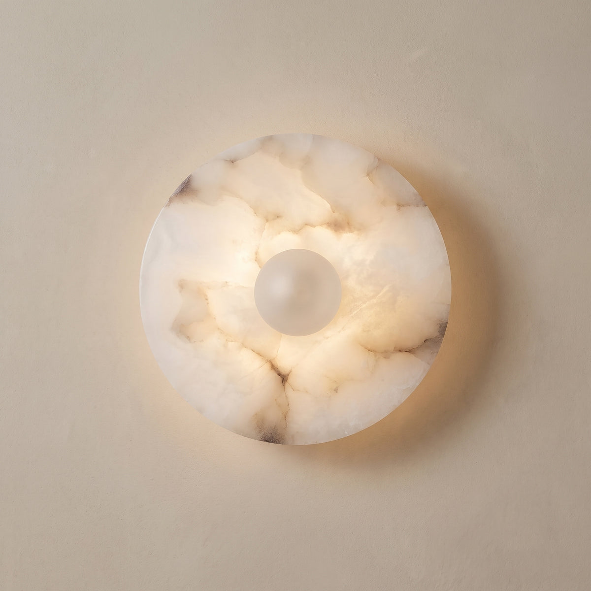 Alba alabaster wall sconce, round veined disc with white globe, studio shot on a neutral backdrop