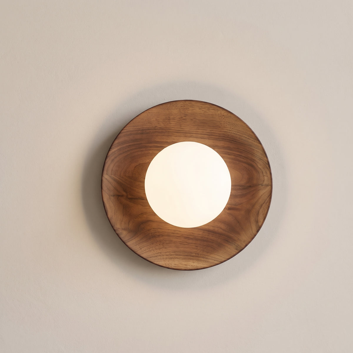Japandi wood globe wall sconce in walnut, studio shot on a neutral backdrop