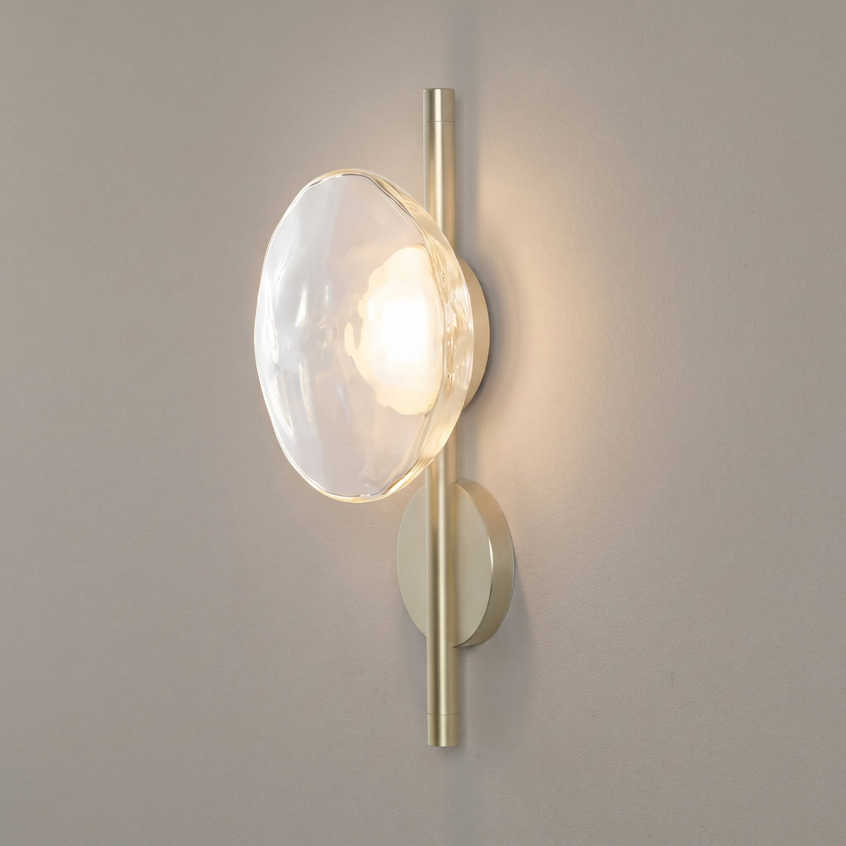 Ceto round glass wall sconce, single clear disc on gold, studio shot on a neutral backdrop
