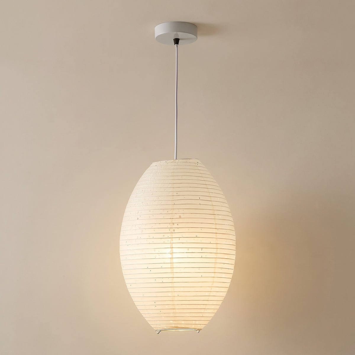 Japandi elliptical paper pendant light, cream lantern shade with white canopy, studio shot on a neutral backdrop